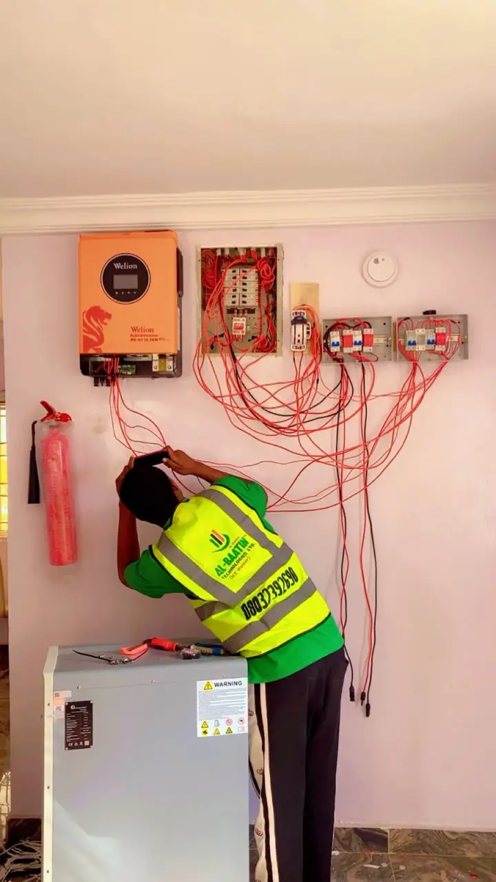 A technician wiring the inverter to the battery below it.