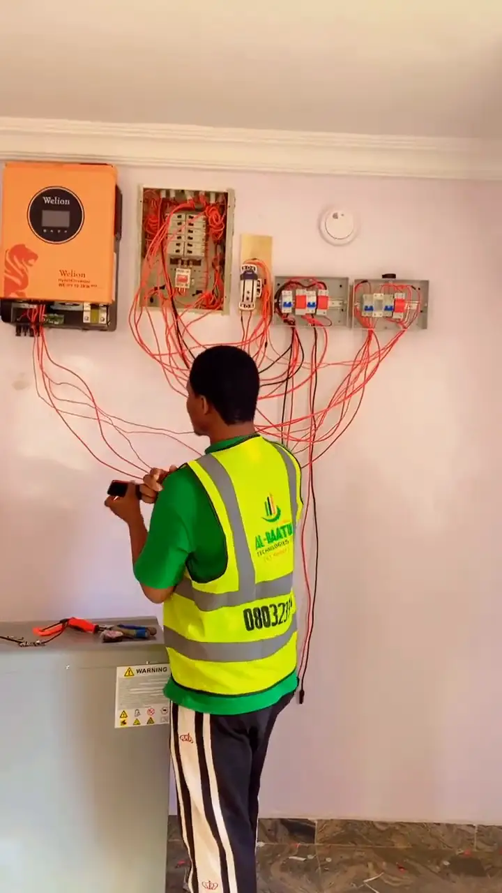 A technician wiring the inverter wall and breakers.