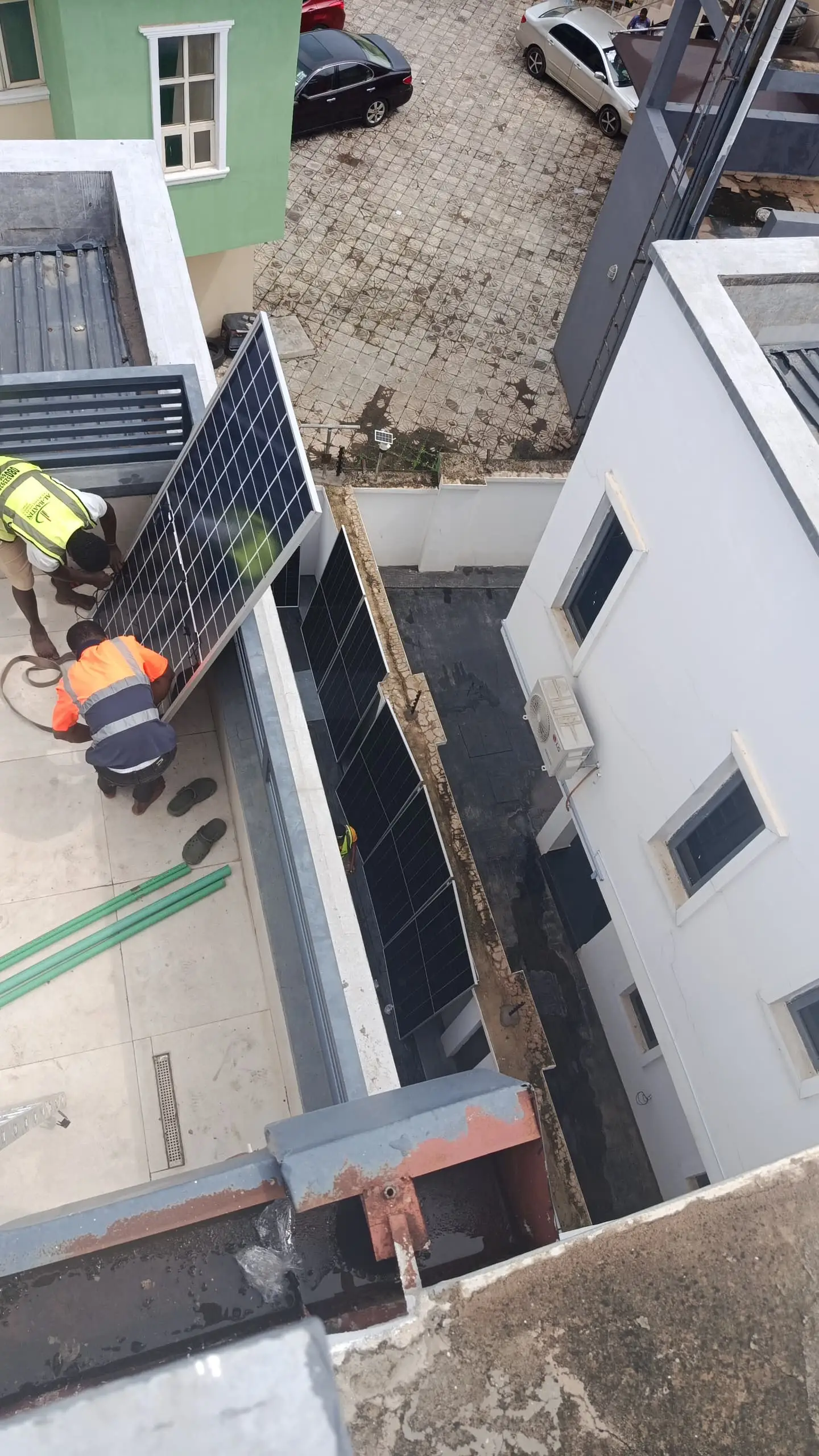Fitters handing a solar panel up to the roof from a balcony.