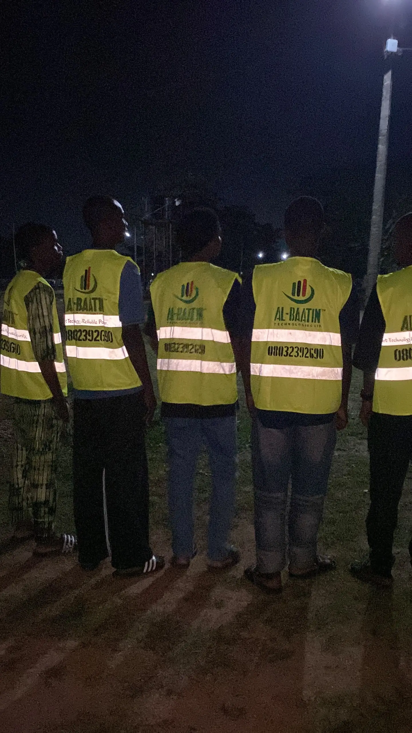 The crew in branded hi-vis vests photographed in the evening, the company name and phone number across the back of each vest.